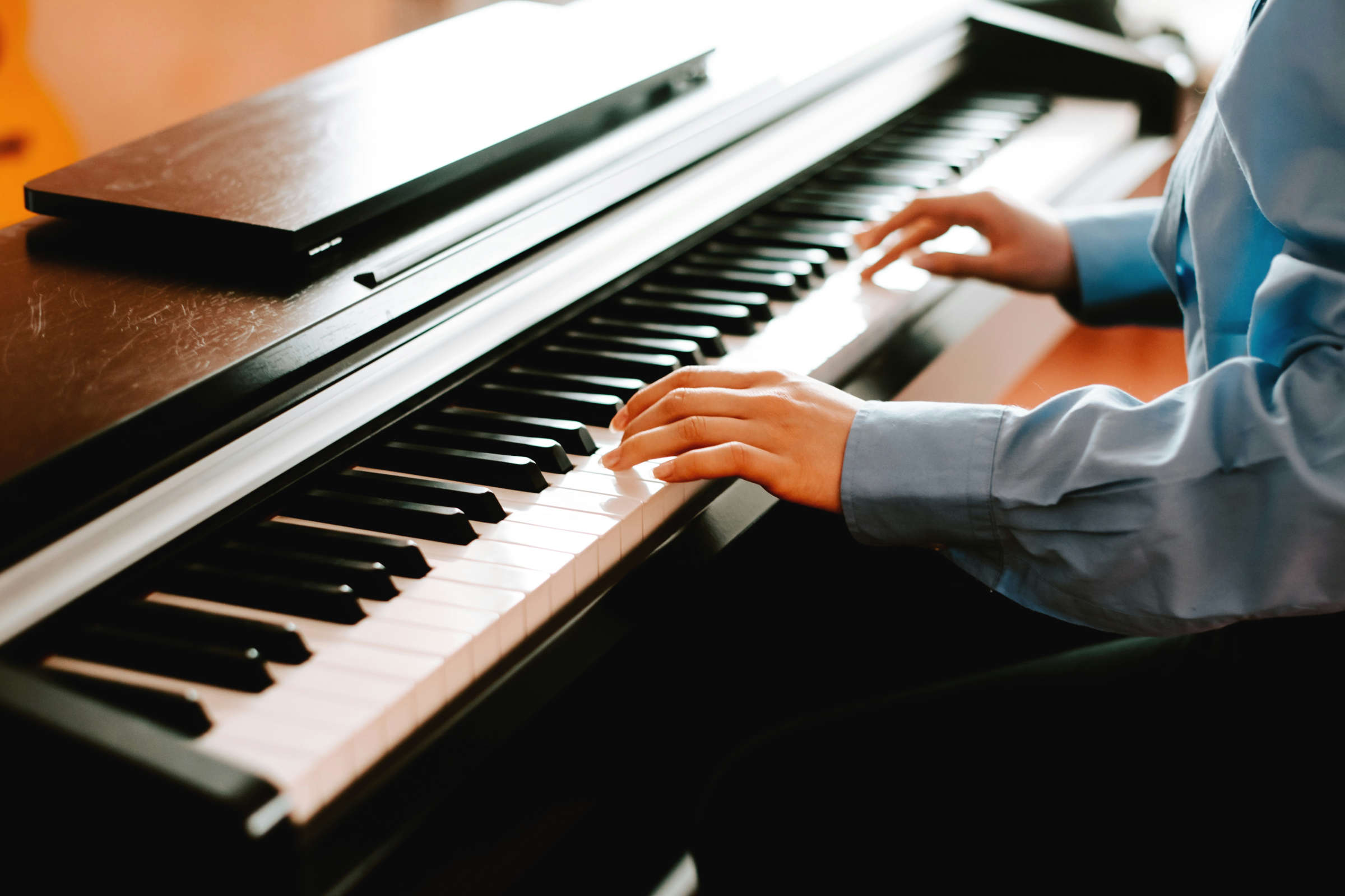 junge Frau in blauer Bluse spielt Klavier